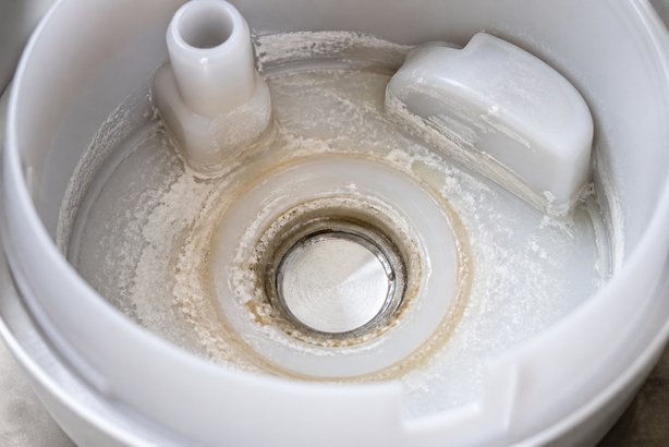 close up of a diffuser tank showing mineral scale and residue buildup on the ultrasonic plate from hard water use