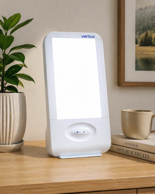 verilux happylight liberty light therapy lamp on a wooden surface with a plant and coffee cup