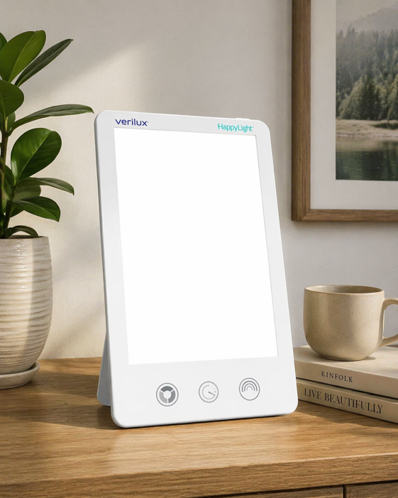 verilux happylight luxe light therapy lamp on a wooden surface with a plant and coffee cup