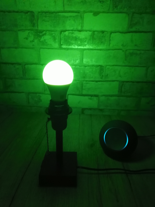 innr smart bulb glowing green in a lamp next to an echo dot max